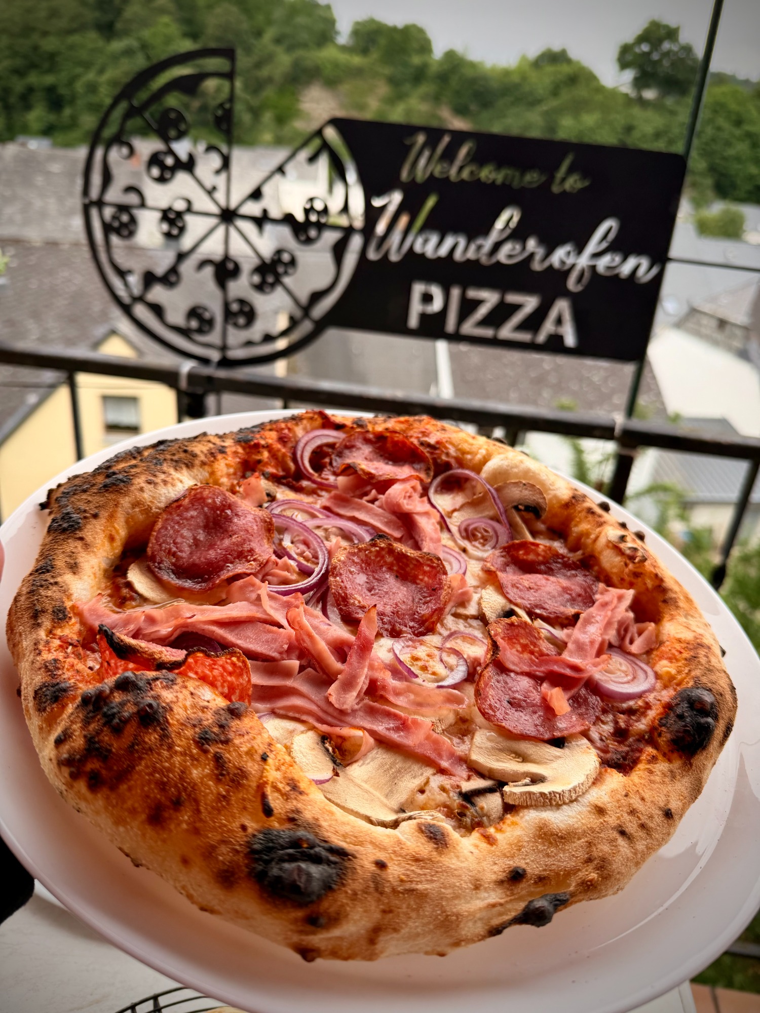 Frisch gebackene Pizza mit Salami, Schinken und Zwiebeln